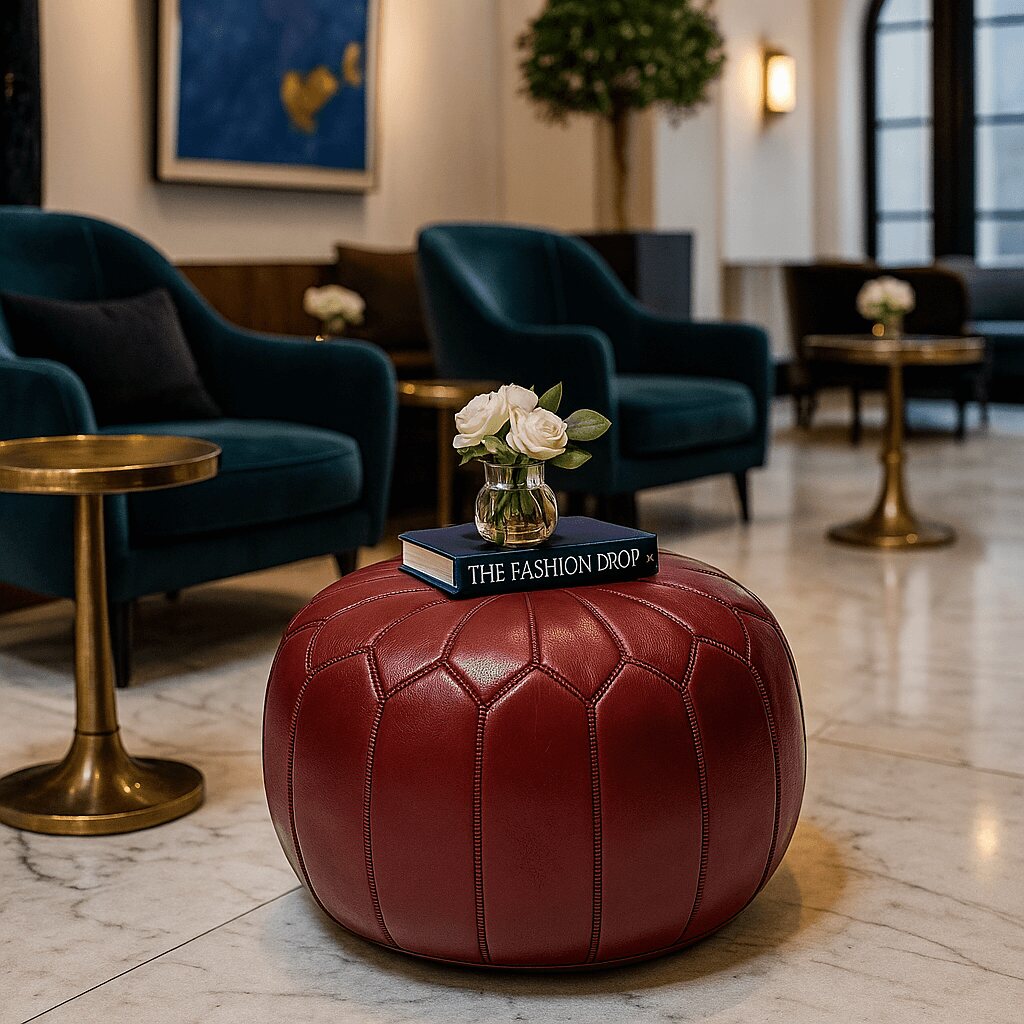Deep red leather pouf in a boutique lounge with teal armchairs and gold tables