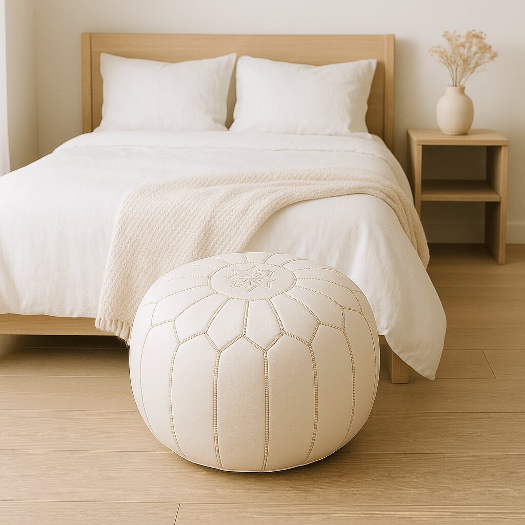 White leather pouf at the foot of a minimalist bed in a serene bedroom