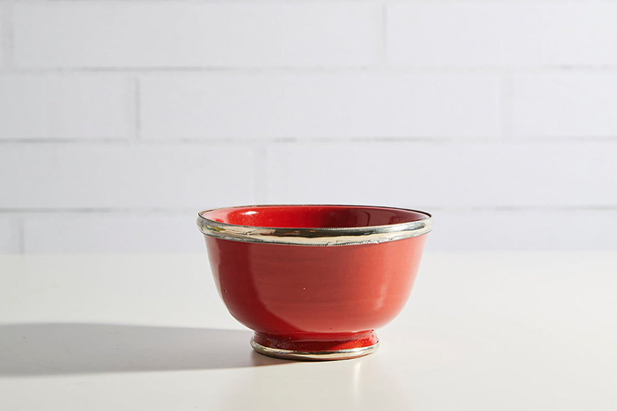 Red glazed ceramic bowl with metallic silver trim around rim and base.