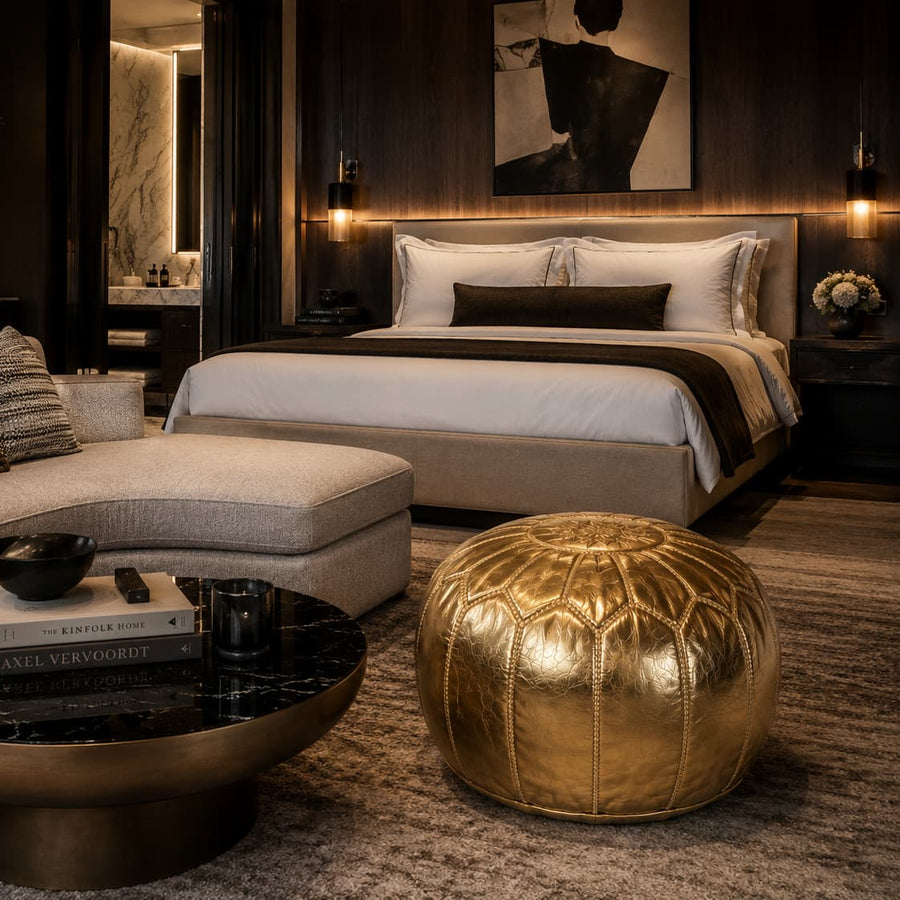 Gold Moroccan pouf in a luxury bedroom lounge area with boucle armchairs and a city skyline at dusk