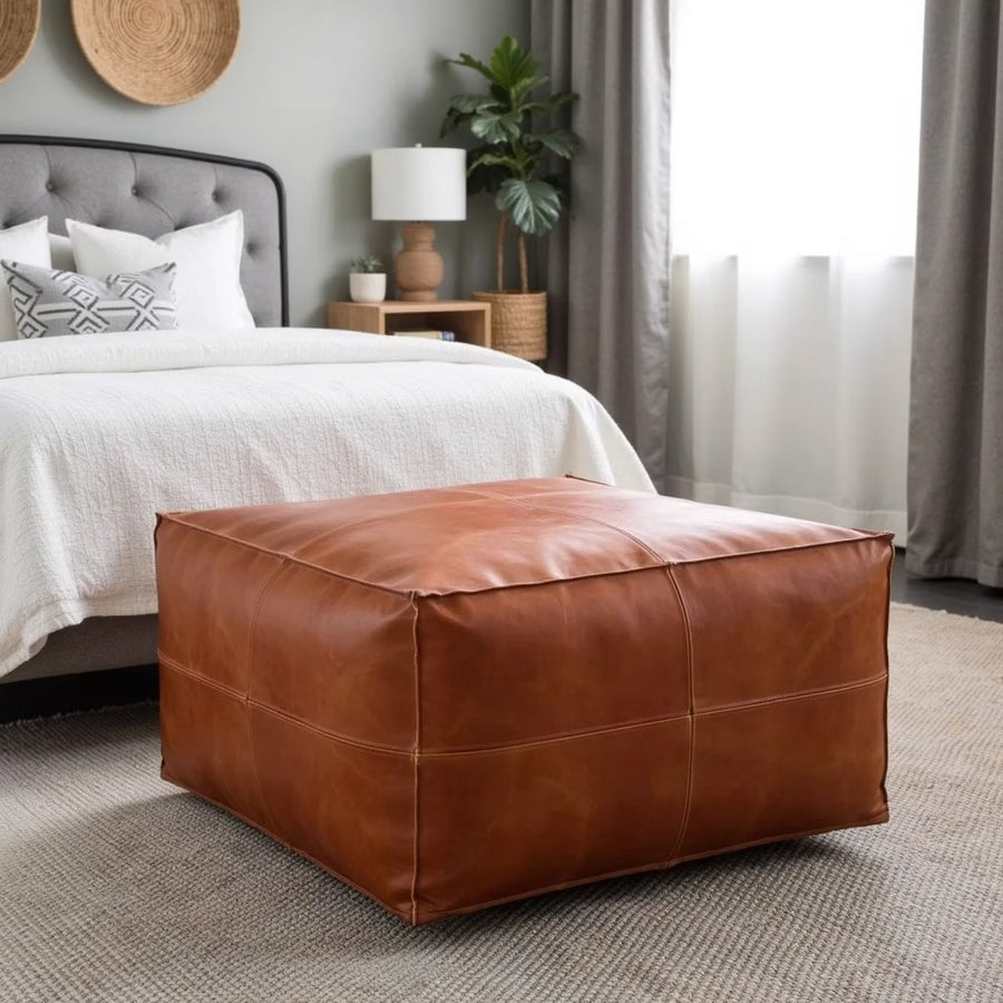 Light brown square leather pouf beside a fireplace with a woven rug