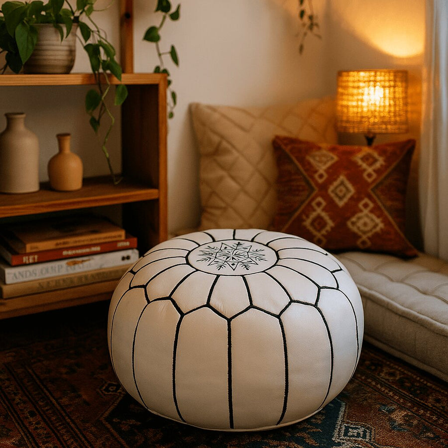 White leather pouf in a reading nook with a patterned rug, cushions and warm lamplight
