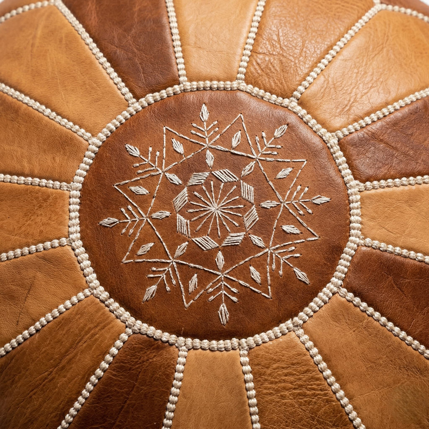 Close-up of the hand-embroidered eight-pointed star and cream whipstitch seams on the pouf top panel