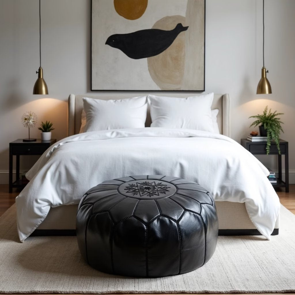 Black hand-stitched leather pouf on a plain studio background