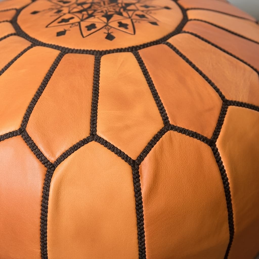Tan leather round ottoman, close view of the hand-stitched panel seams