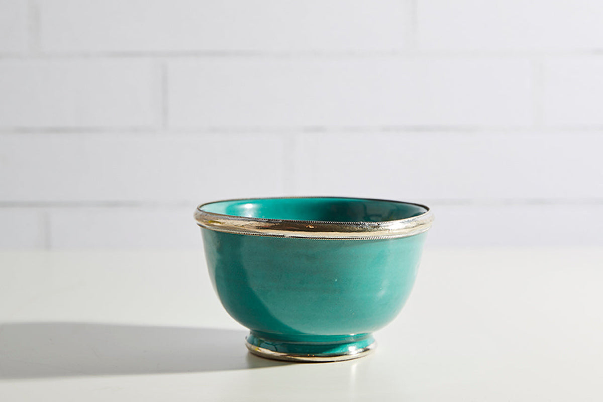 Turquoise glazed ceramic bowl with metallic silver trim around the rim and base.