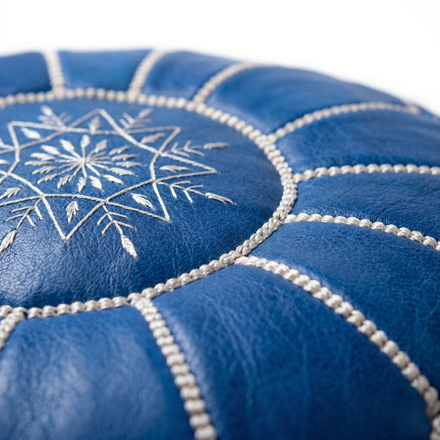 Close-up of the hand-embroidered off-white star motif and contrast seam stitching on the denim blue leather pouf