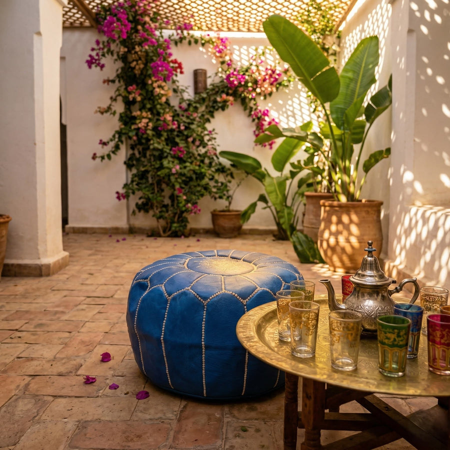 Denim blue leather pouf in a Marrakech riad courtyard beside a brass tea tray and Moroccan tea glasses