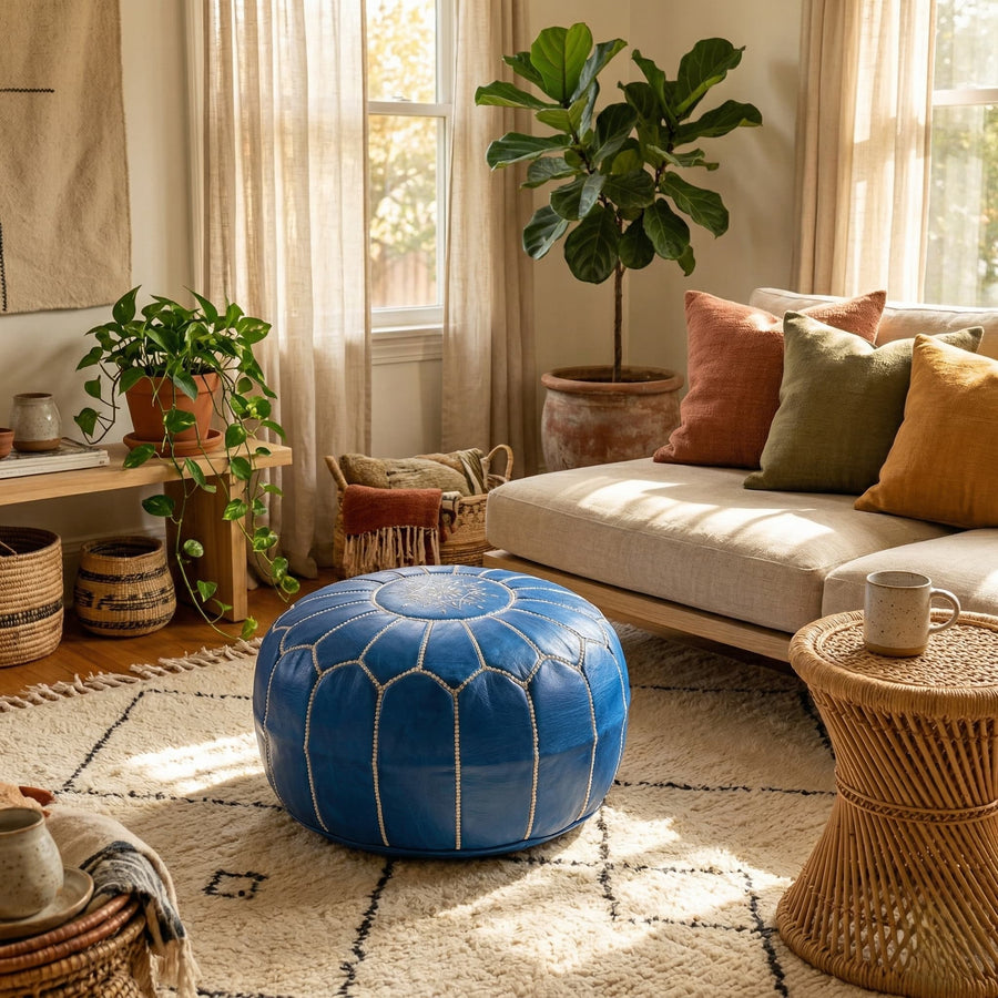 Denim blue Moroccan pouf used as a footstool in a sunlit living room with a Beni Ourain rug