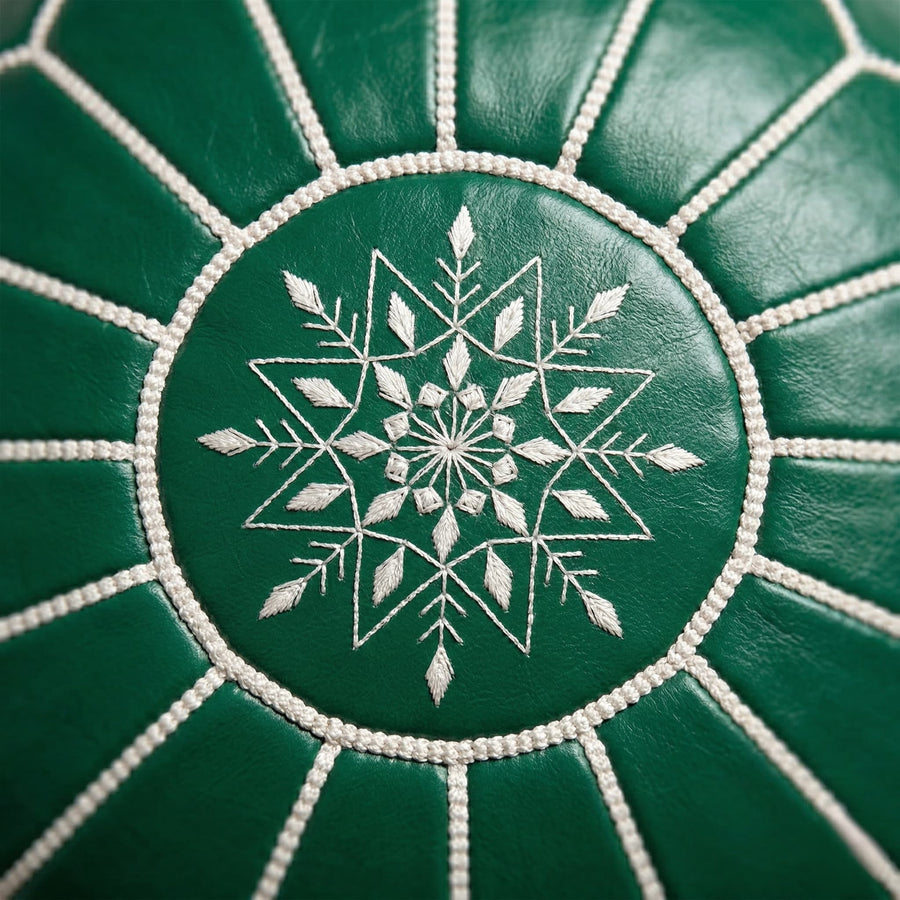 Close-up of the hand-embroidered white eight-pointed star and whipstitch seams on the green leather pouf top panel