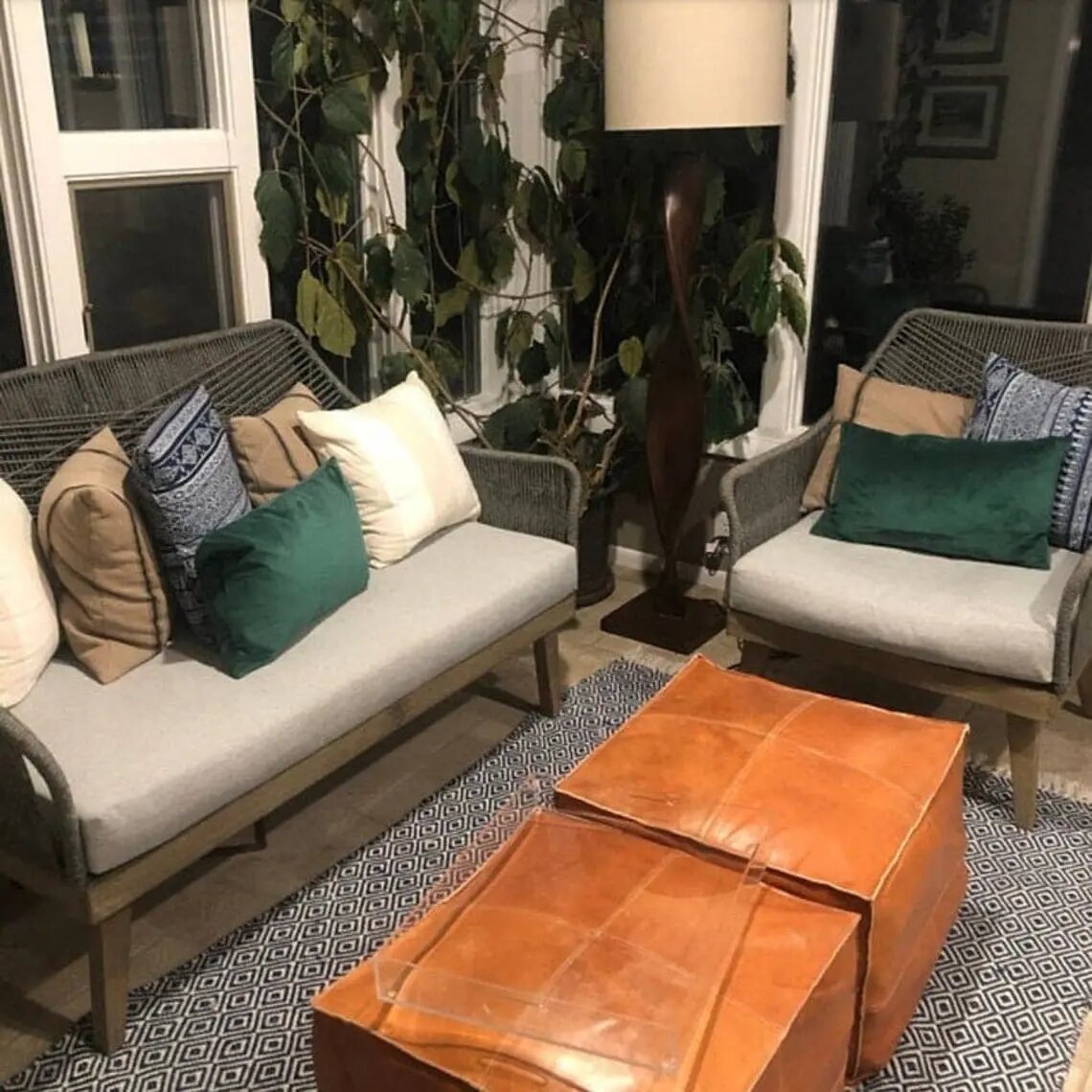 Large brown square leather ottoman used as a low centre table in a seating area