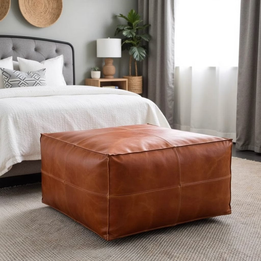 Light brown square leather pouf beside a fireplace with a woven rug
