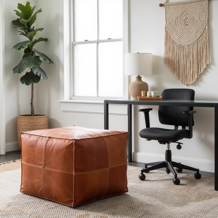 Light brown square leather ottoman in a bedroom at the foot of a bed