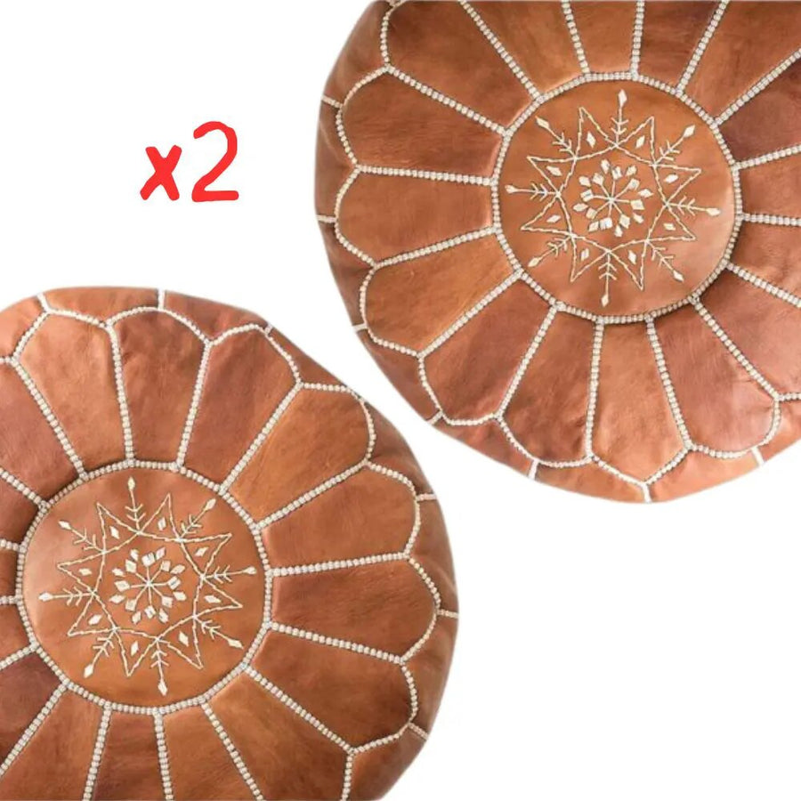 Set of two tan Moroccan leather round poufs with cream star embroidery, on a plain white background