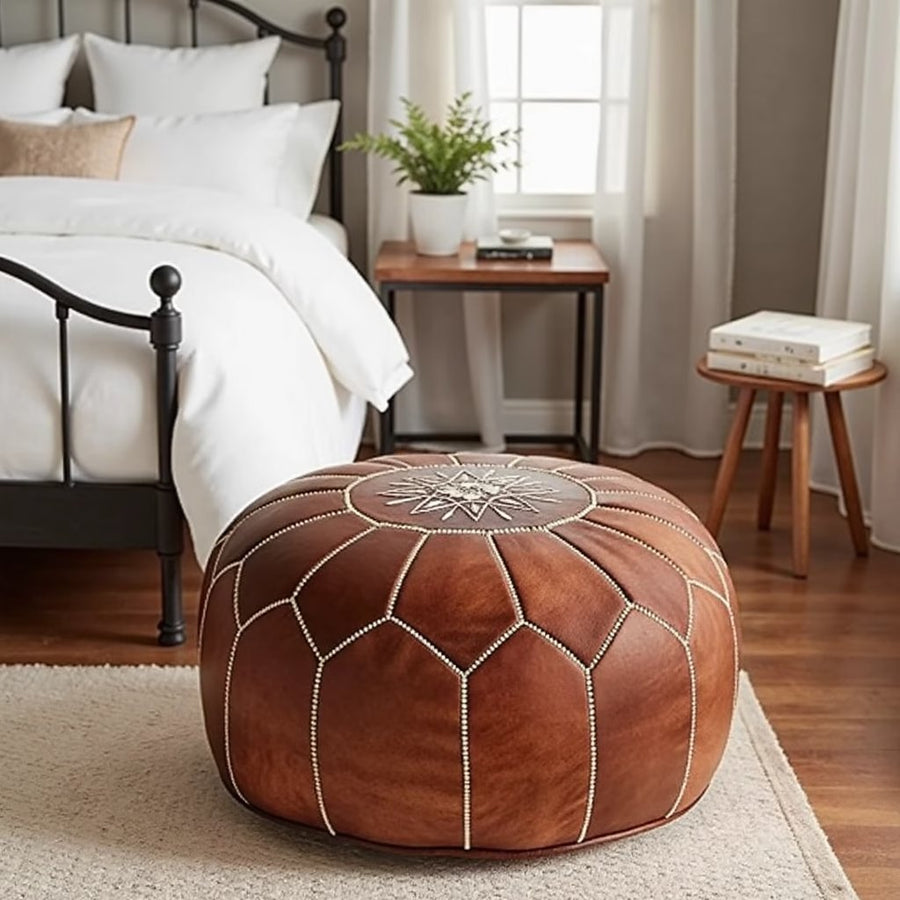 Tan leather pouf beside a potted plant in a bright minimalist corner