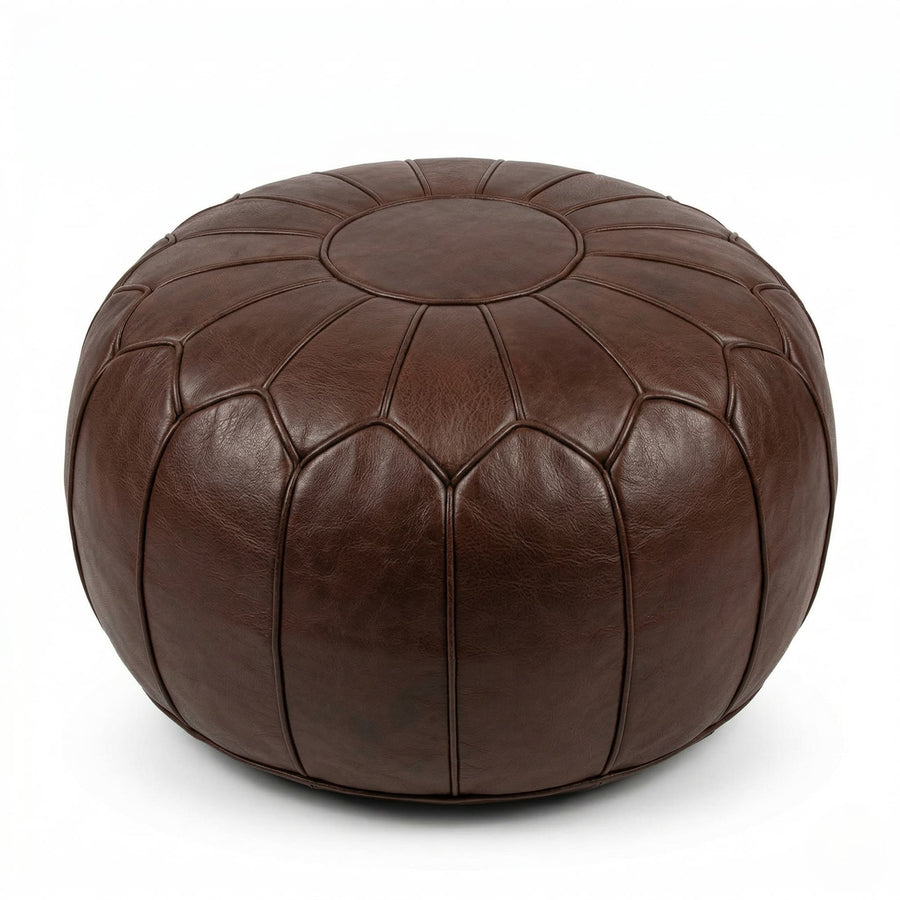 Chocolate brown leather pouf beside a cream sofa with a knitted throw