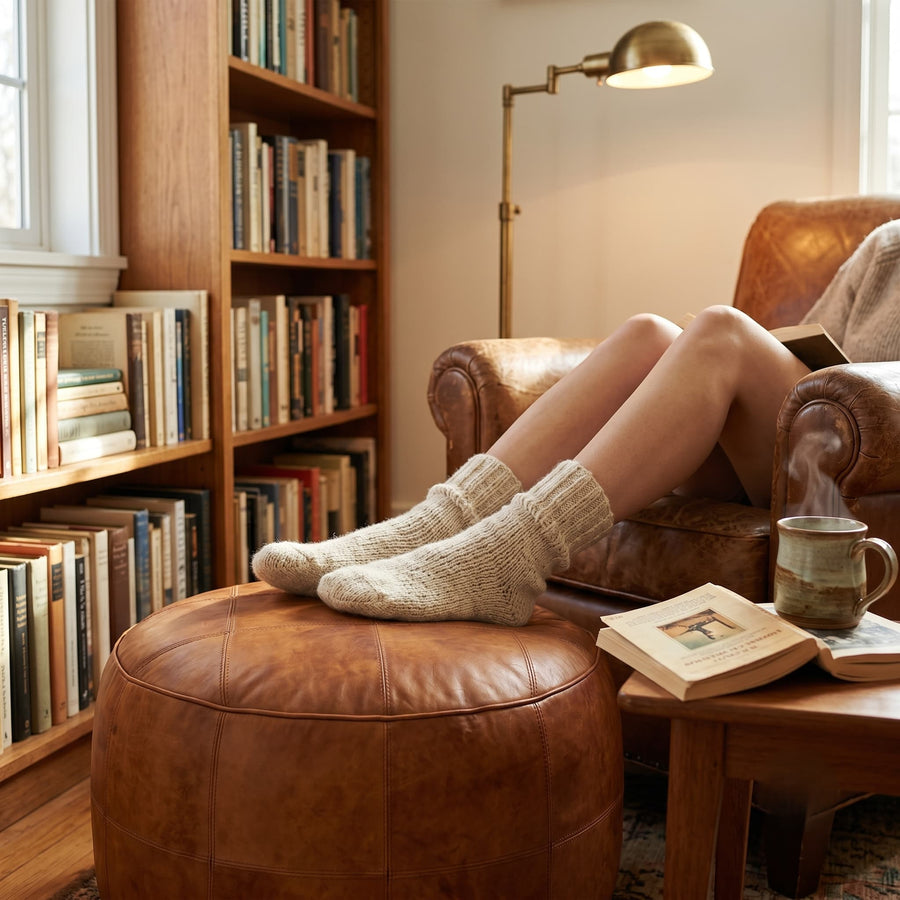 Tan leather floor ottoman with a draped throw in a cozy reading nook