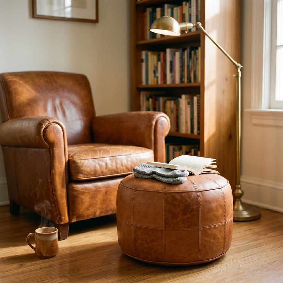 Tan leather floor ottoman paired with a vintage armchair on a patterned rug