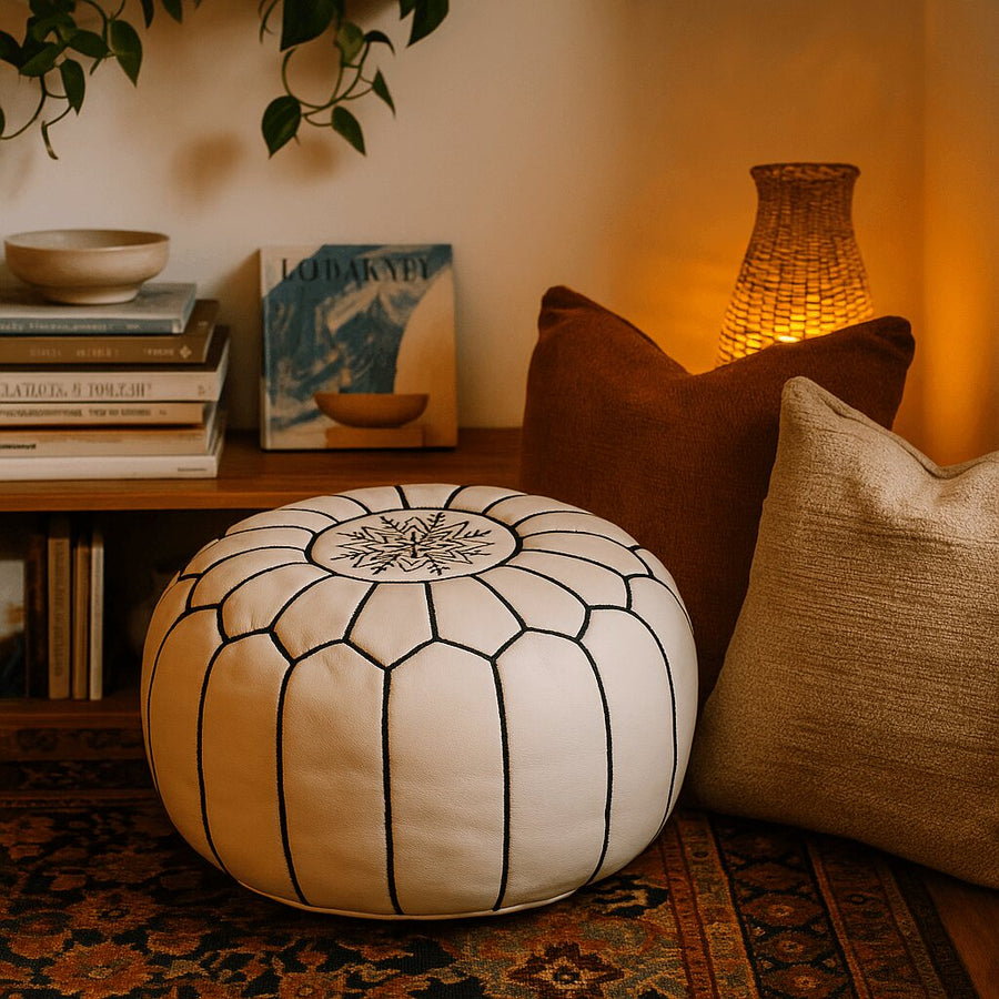 White leather pouf between earth-toned cushions and bookshelves in a bohemian corner